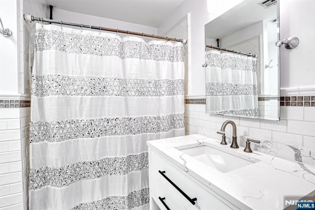 1110 River Road, Unit 105 Edgewater, NJ 07020 - Photo 14 of 19 a bathroom with a sink and a large mirror