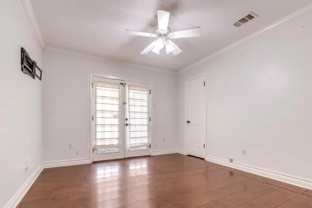 an empty room with wooden floor chandelier fan and windows