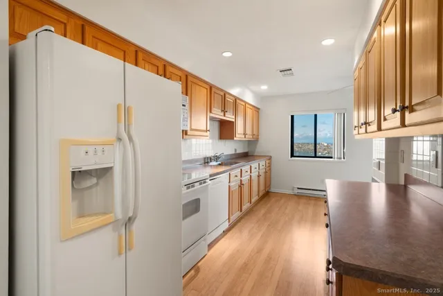 a kitchen with stainless steel appliances granite countertop a refrigerator a stove and a sink with wooden floor