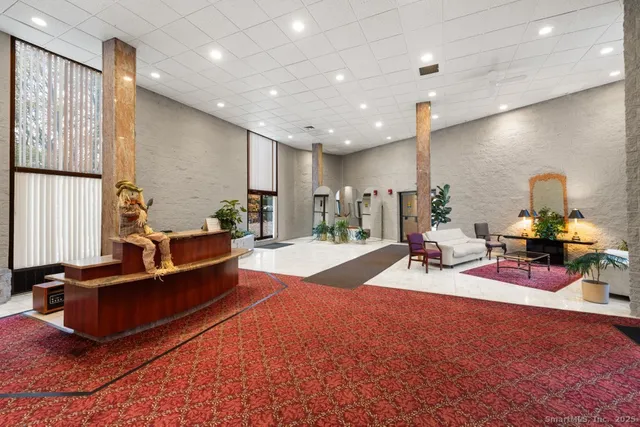 a living room with furniture a rug kitchen view and a large window