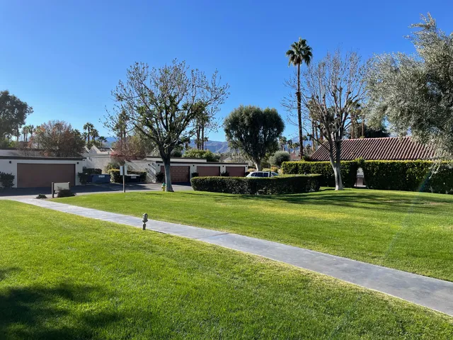 a view of a house with a big yard and palm trees