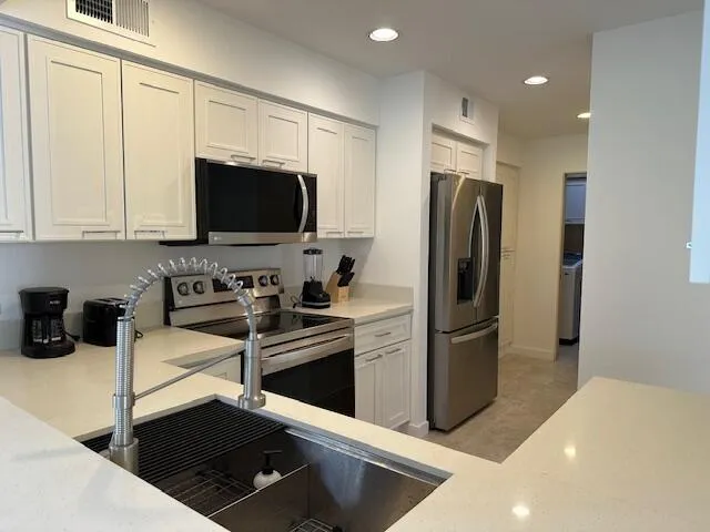 a kitchen with stainless steel appliances granite countertop a refrigerator and a stove top oven