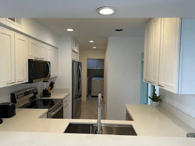 a kitchen with stainless steel appliances kitchen island granite countertop a refrigerator and a sink