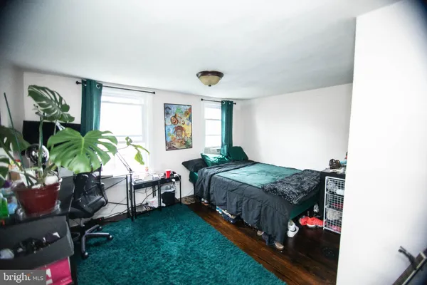 a bedroom with a bed table chair and a window