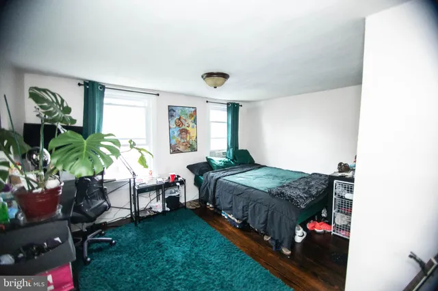 a bedroom with a bed table chair and a window