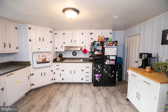 a kitchen with stainless steel appliances a stove top oven a refrigerator a sink and white cabinets