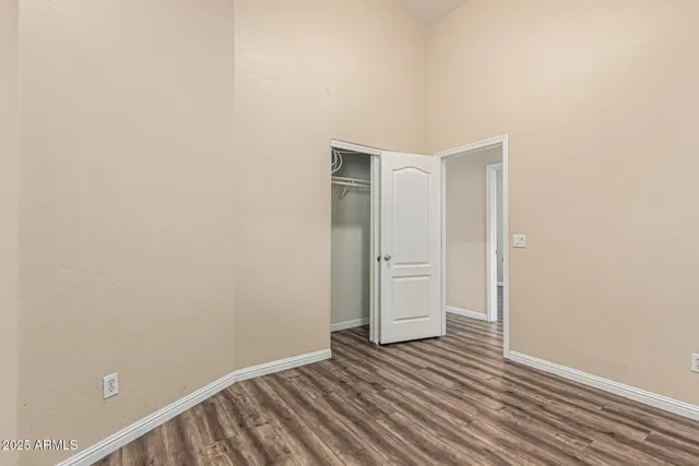 a view of an empty room with wooden floor and closet
