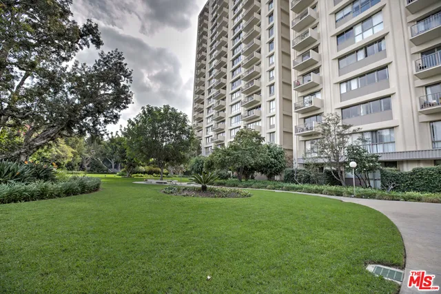 a view of a big building with a big yard and large trees