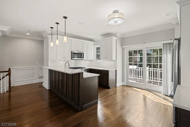 a kitchen with granite countertop a stove a sink and a refrigerator with wooden floor