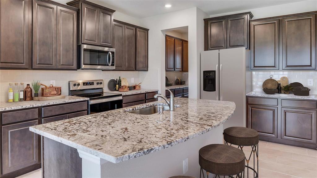 11975 Kingsley Trail Parrish, FL 34219 - Photo 4 of 26 a kitchen with stainless steel appliances granite countertop a sink a stove and refrigerator