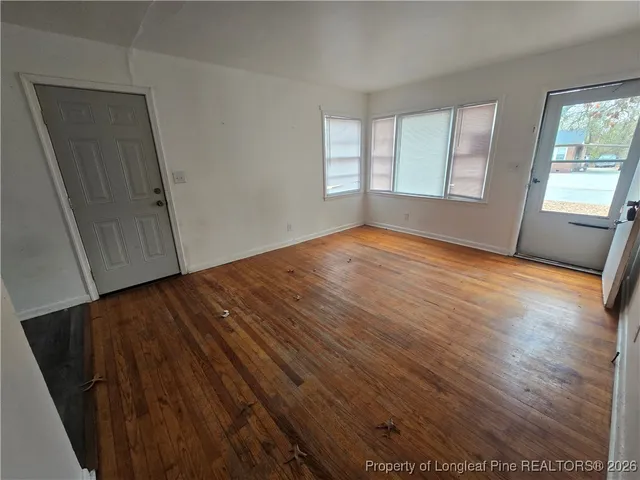 an empty room with wooden floor and windows