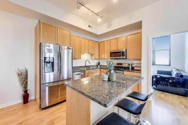 a kitchen with stainless steel appliances granite countertop a refrigerator a stove top oven a sink and a refrigerator