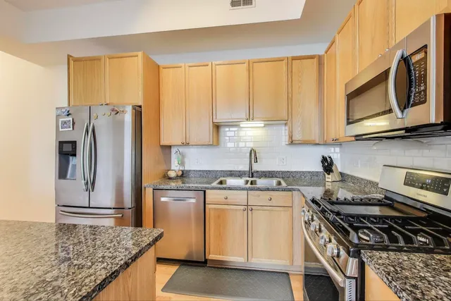 a kitchen with stainless steel appliances granite countertop a stove a sink and a microwave