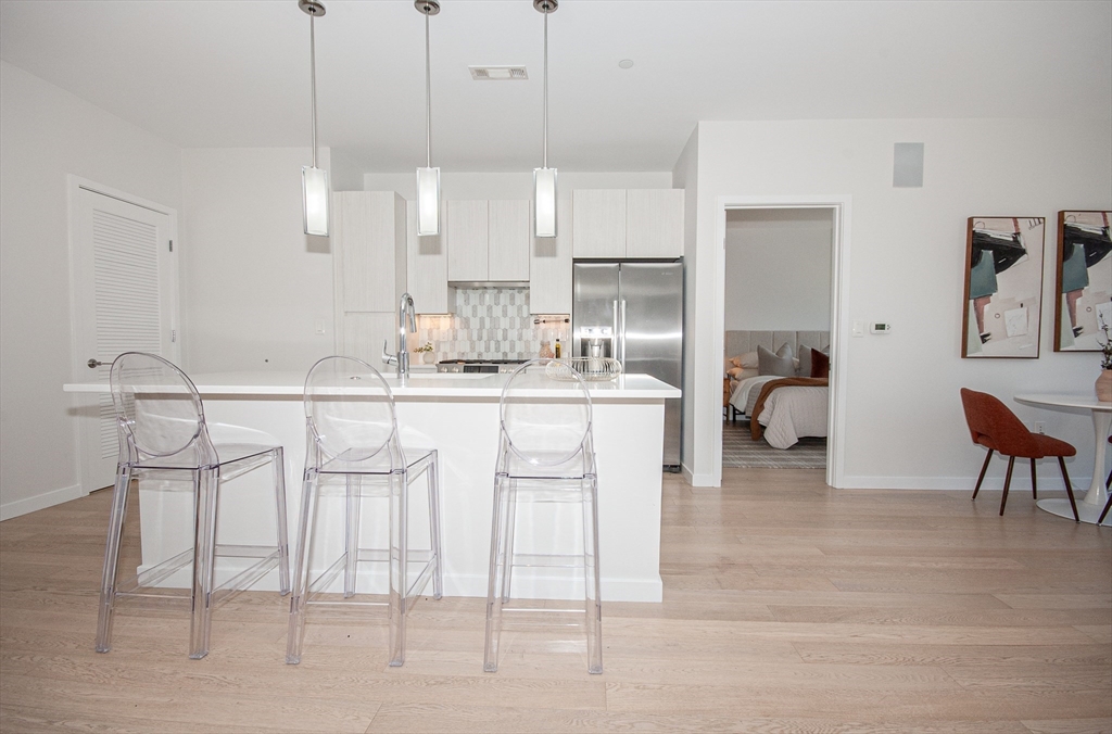 45 West 3rd Street, Unit 409 Boston, MA 02127 - Photo 11 of 30 a kitchen with stainless steel appliances kitchen island granite countertop a table chairs sink and cabinets