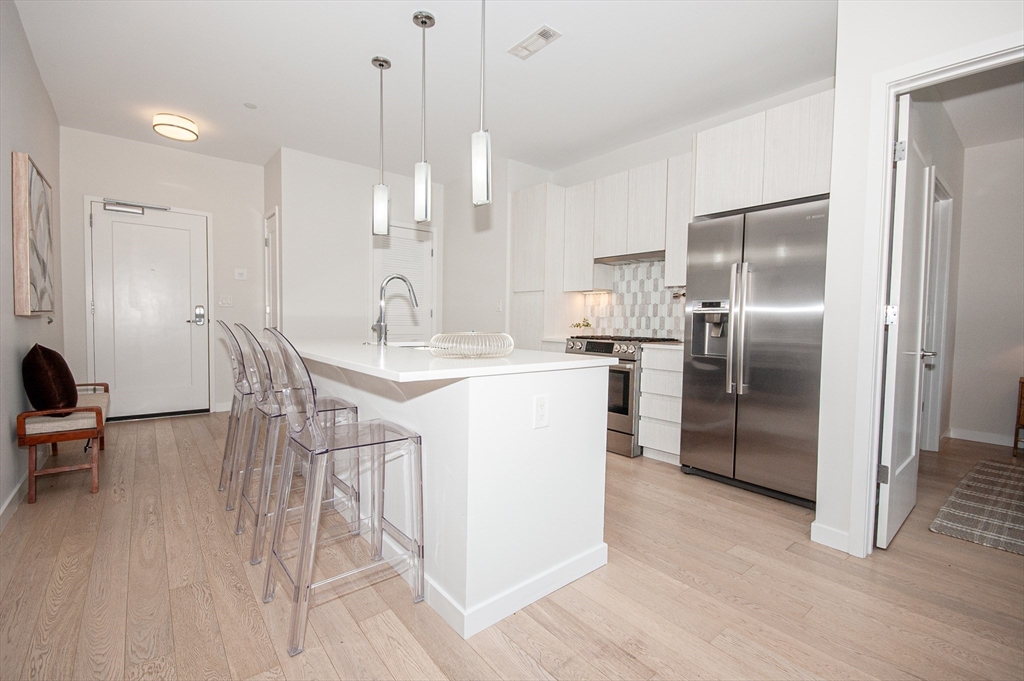45 West 3rd Street, Unit 409 Boston, MA 02127 - Photo 12 of 30 a kitchen with kitchen island a counter top space a sink appliances and cabinets