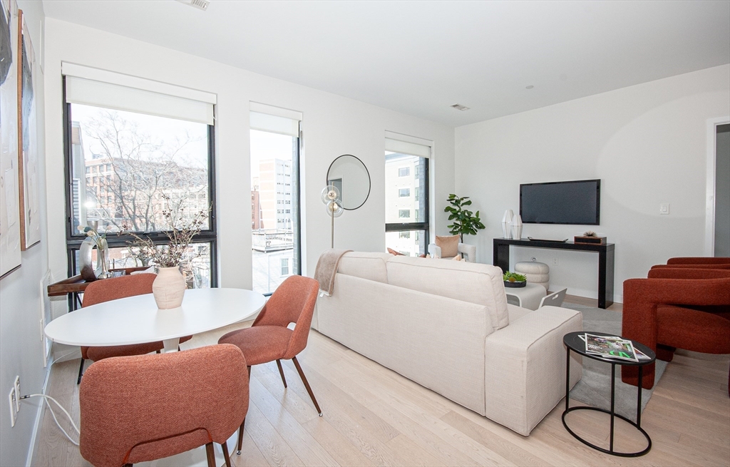 45 West 3rd Street, Unit 409 Boston, MA 02127 - Photo 8 of 30 a living room with furniture a flat screen tv and a floor to ceiling window