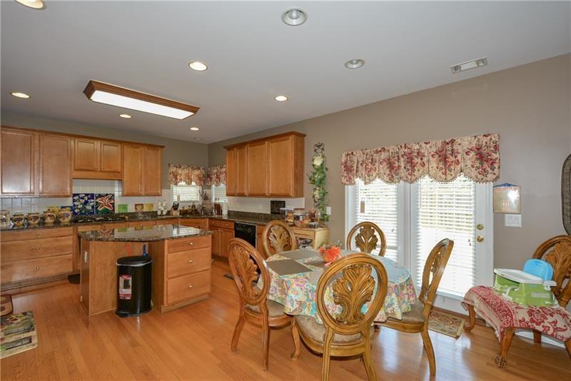172 Villa Pl Court Tucker, GA 30084 - Photo 9 of 18 a kitchen with stainless steel appliances granite countertop a stove top oven a sink a dining table and chairs with wooden floor
