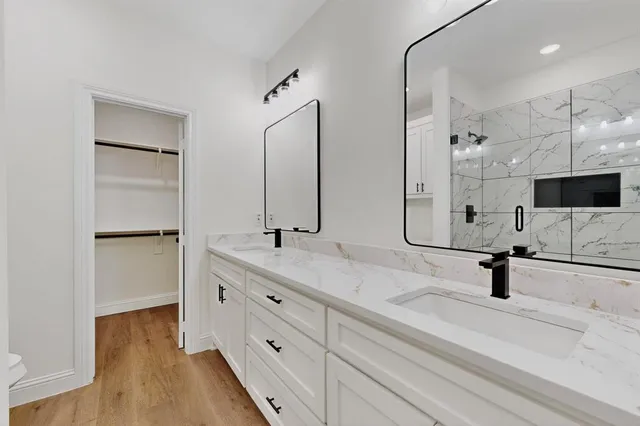 a bathroom with a double vanity sink a mirror and shower