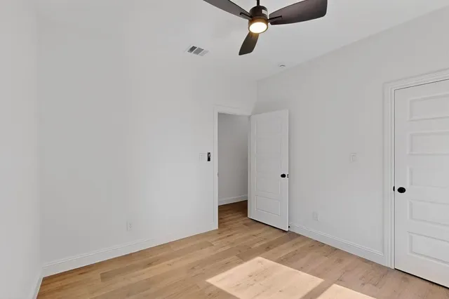 a view of a room with a ceiling fan and wooden floor