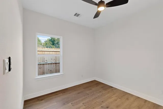 a view of an empty room with wooden floor and a window