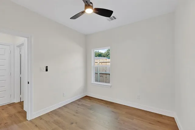 an empty room with wooden floor cabinet and windows