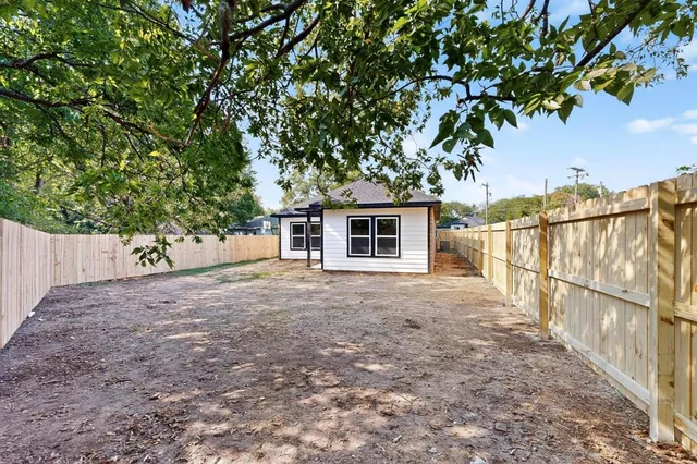 a view of a backyard with wooden fence and large trees