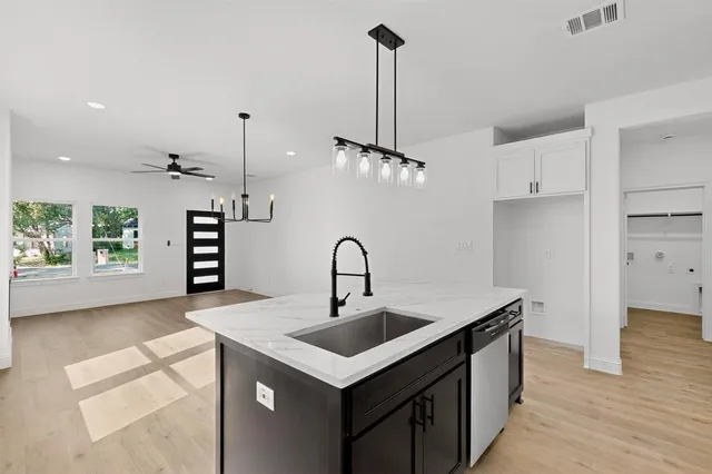 a kitchen with a sink a counter space appliances and cabinets