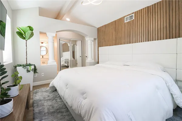 a large white bed sitting in a bedroom next to a window