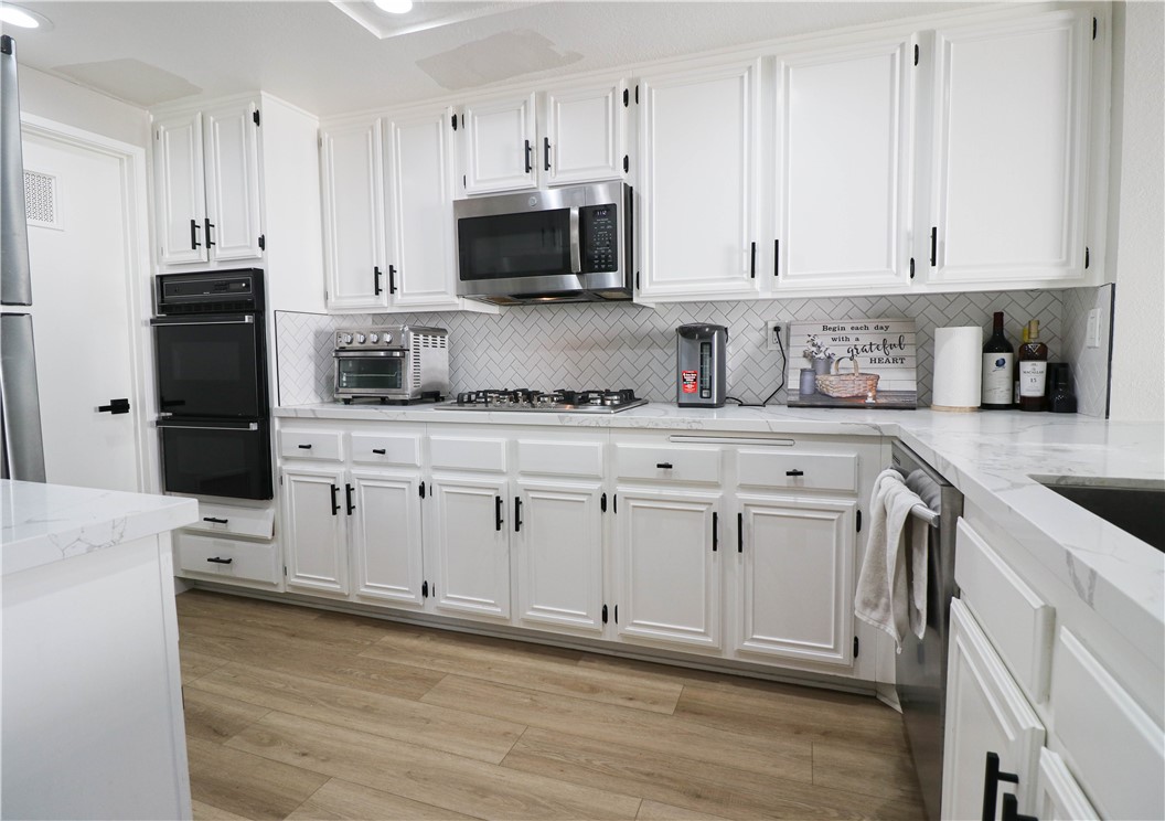 730 Breeze Hill Road, Unit 230 Vista, CA 92081 - Photo 6 of 40 a kitchen with granite countertop white cabinets white stainless steel appliances and sink