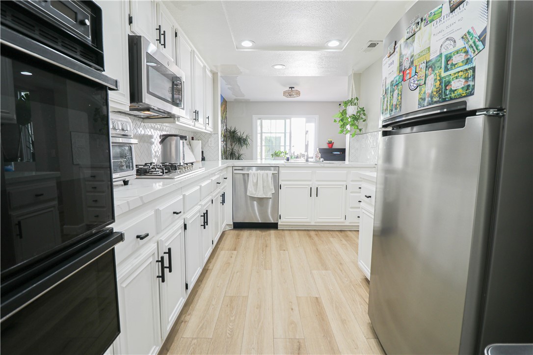 730 Breeze Hill Road, Unit 230 Vista, CA 92081 - Photo 9 of 40 a large white kitchen with stainless steel appliances granite countertop a refrigerator a sink dishwasher a stove and white cabinets with wooden floor