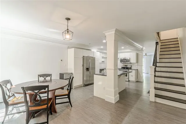 a room with stainless steel appliances kitchen island granite countertop a stove a sink and a refrigerator with wooden floor