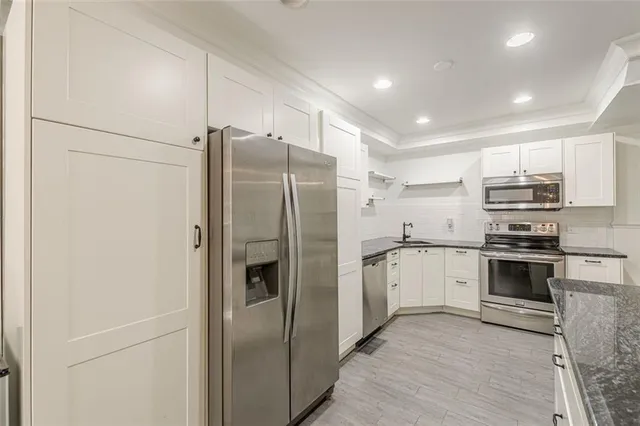 a kitchen with granite countertop a stove and white cabinets