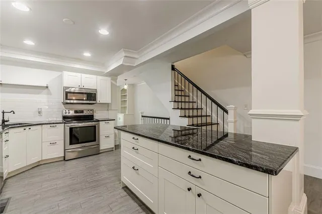 a kitchen with granite countertop white cabinets stainless steel appliances and a counter space