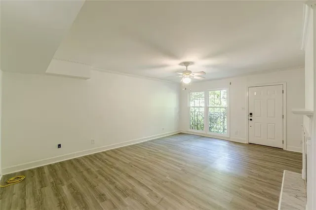 an empty room with wooden floor fireplace and windows