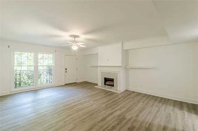 an empty room with wooden floor fireplace and windows