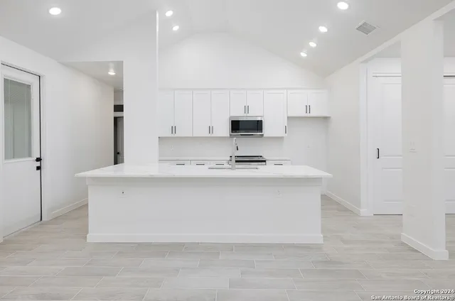 a kitchen with kitchen island a sink a stove a refrigerator and white cabinets