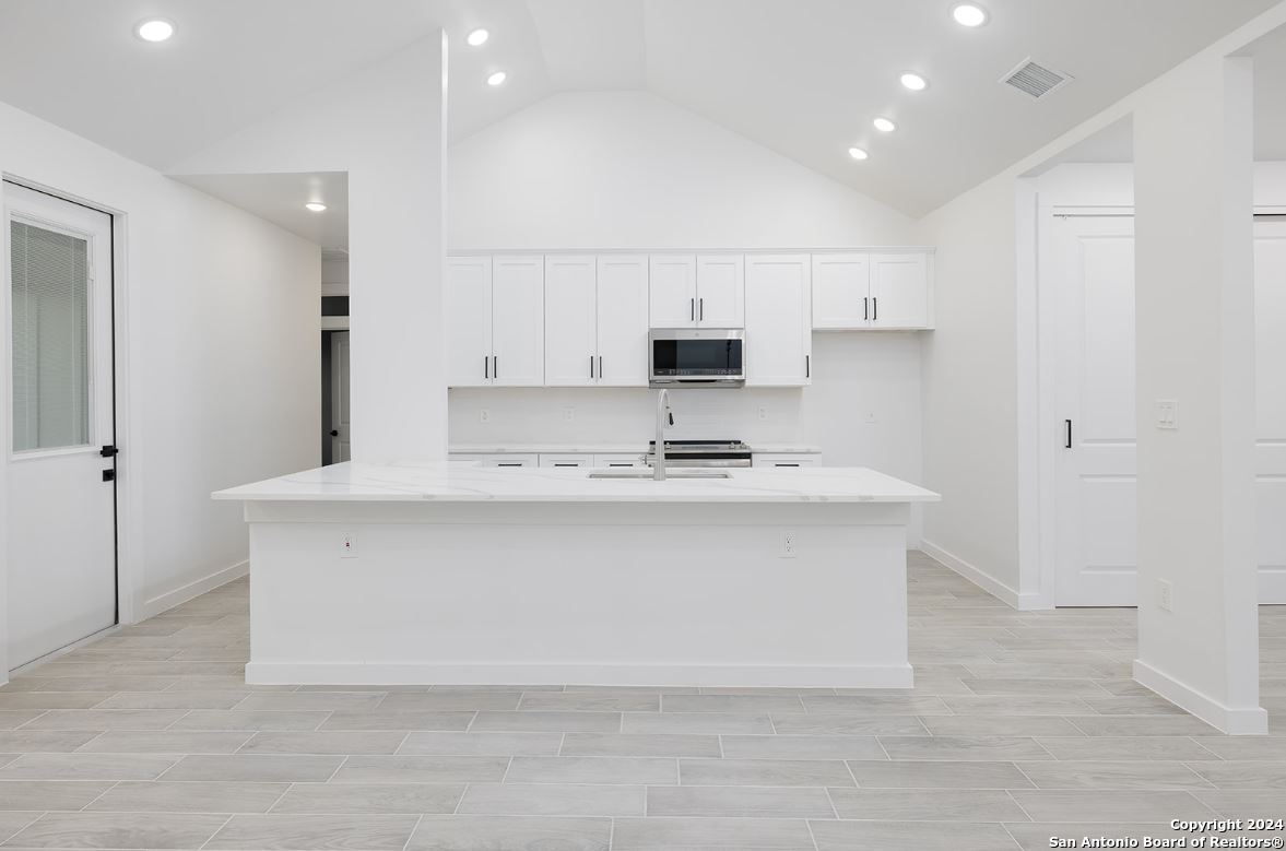 329 Blue Bonnet Breeze Spring Branch, TX 78070 - Photo 5 of 20 a kitchen with kitchen island a sink a stove a refrigerator and white cabinets