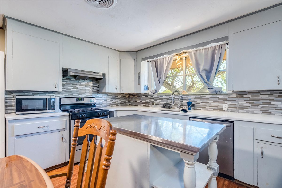 500 Blackjack Street Lockhart, TX 78644 - Photo 11 of 27 Kitchen featuring stainless steel appliances, light countertops, a center island, and white cabinets