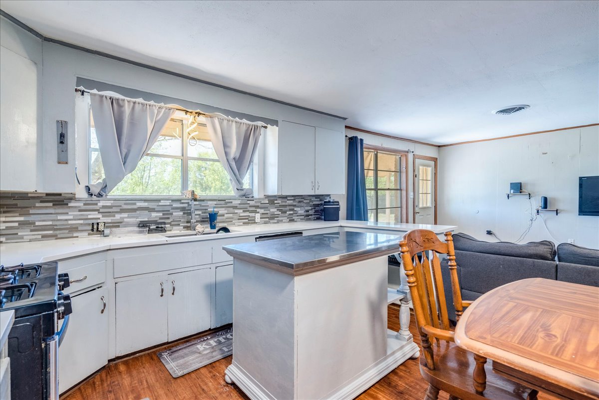 500 Blackjack Street Lockhart, TX 78644 - Photo 27 of 27 Kitchen with white cabinets, stainless steel range with gas cooktop, light wood-style flooring, open floor plan, and a center island