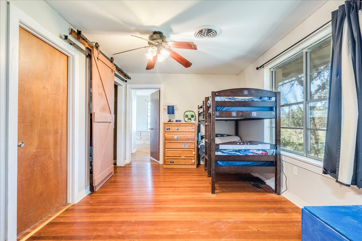 500 Blackjack Street Lockhart, TX 78644 - Photo 16 of 27 Bedroom with a barn door, light wood-type flooring, and a ceiling fan