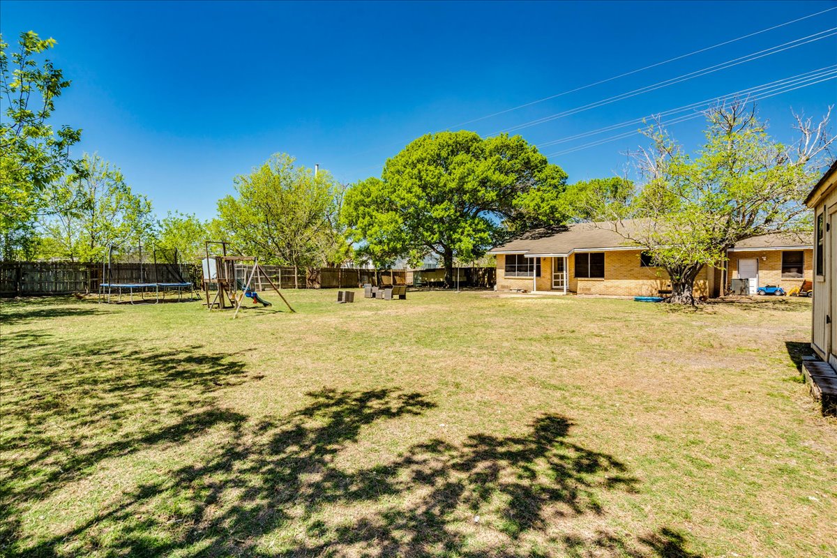 500 Blackjack Street Lockhart, TX 78644 - Photo 23 of 27 Fenced backyard with a playground, a trampoline, and a patio area