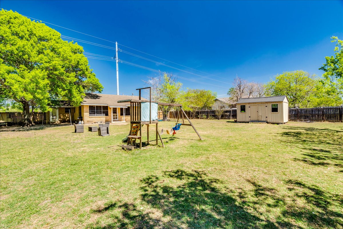500 Blackjack Street Lockhart, TX 78644 - Photo 24 of 27 Fenced backyard featuring a playground, a storage unit, and a patio area
