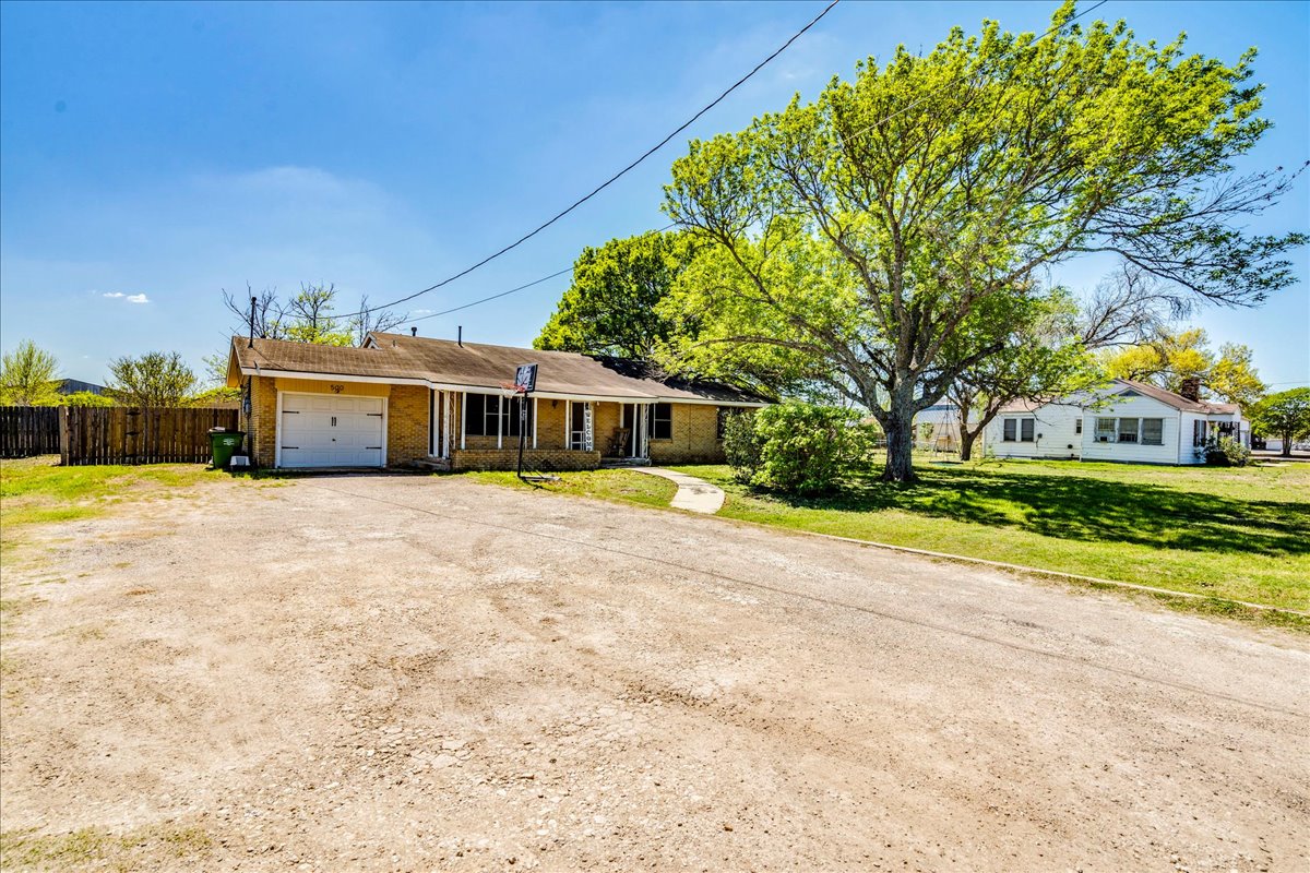 500 Blackjack Street Lockhart, TX 78644 - Photo 5 of 27 Ranch-style home with brick siding, a garage, and dirt driveway