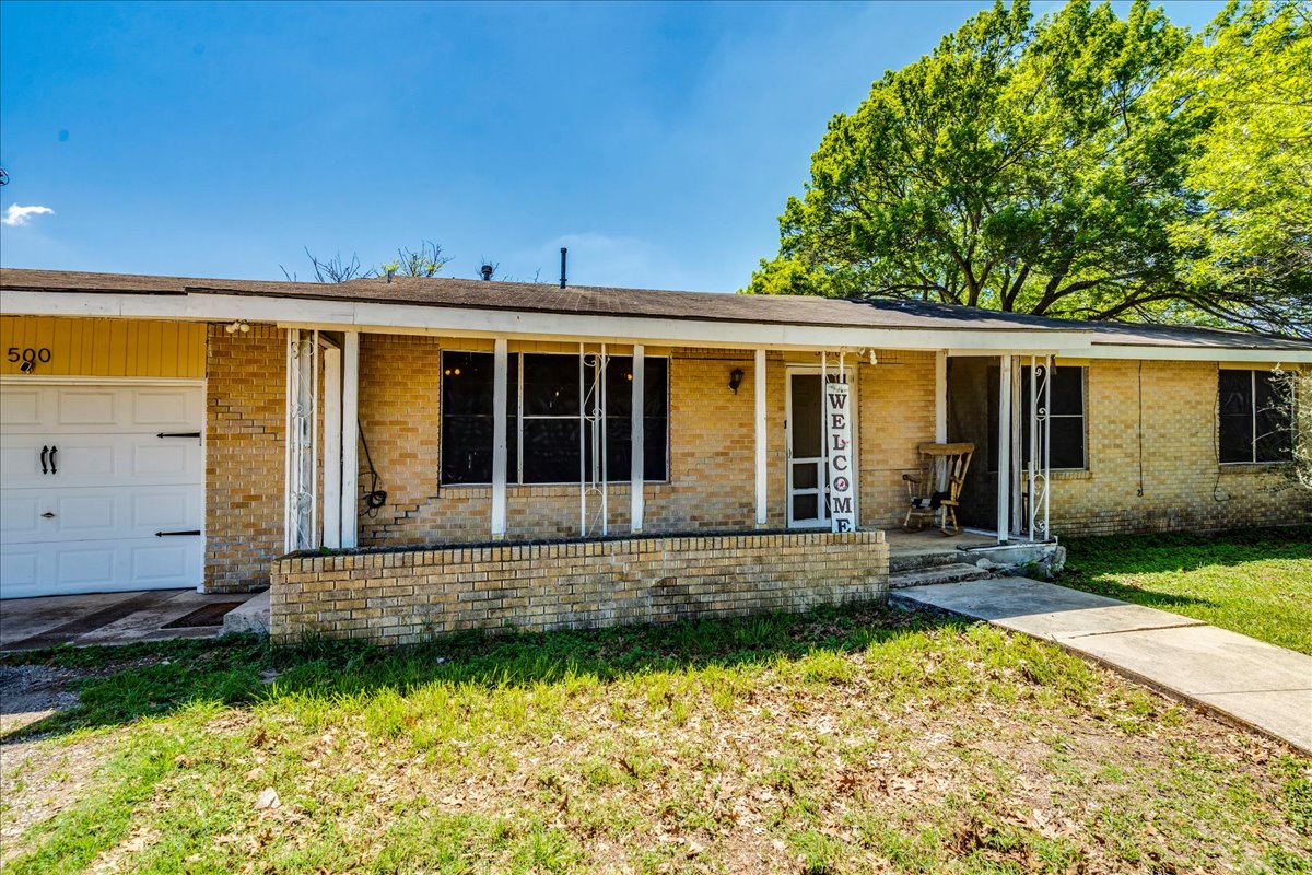 500 Blackjack Street Lockhart, TX 78644 - Photo 6 of 27 Single story home featuring brick siding, covered porch, an attached garage, and a front lawn