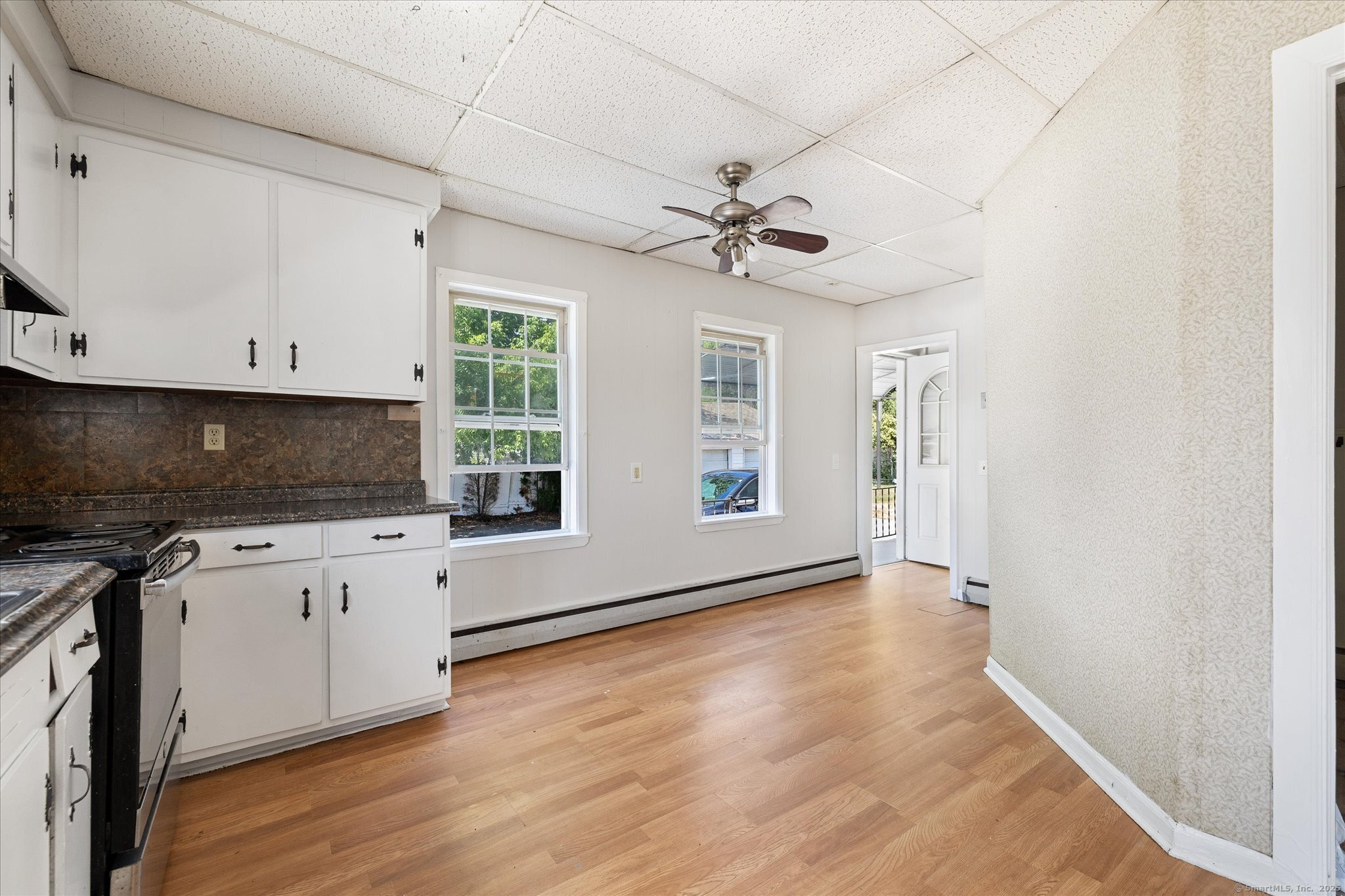 42-44 Church Street Plainfield, CT 06354 - Photo 13 of 36 a kitchen with granite countertop a stove a sink and white cabinets with wooden floor next to windows