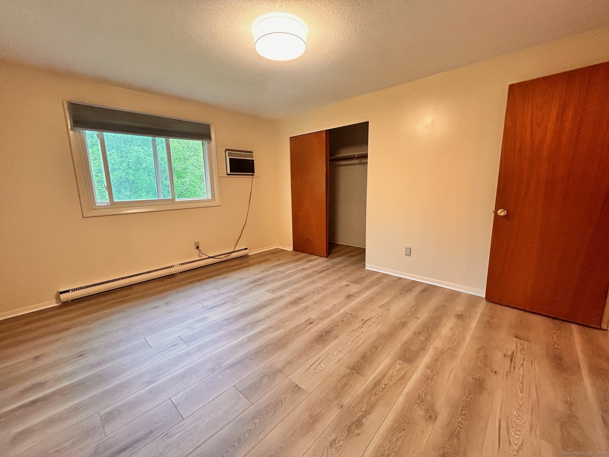 213 Baxter Road, Unit B Storrs Mansfield, CT 06268 - Photo 6 of 12 a view of an empty room with wooden floor and a window