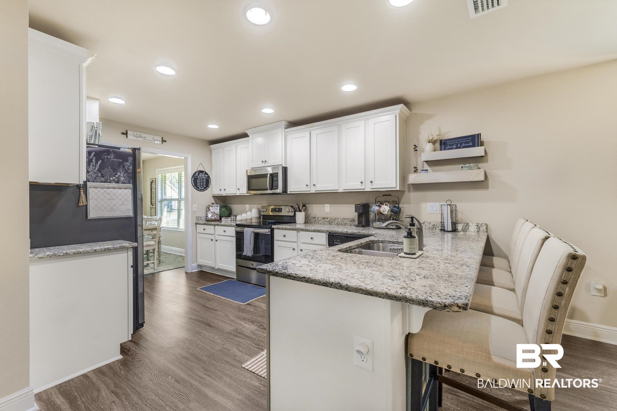 22043 Garland Loop Silverhill, AL 36576 - Photo 11 of 41 Kitchen featuring a peninsula, white cabinetry, a breakfast bar, stainless steel appliances, and dark wood-style floors