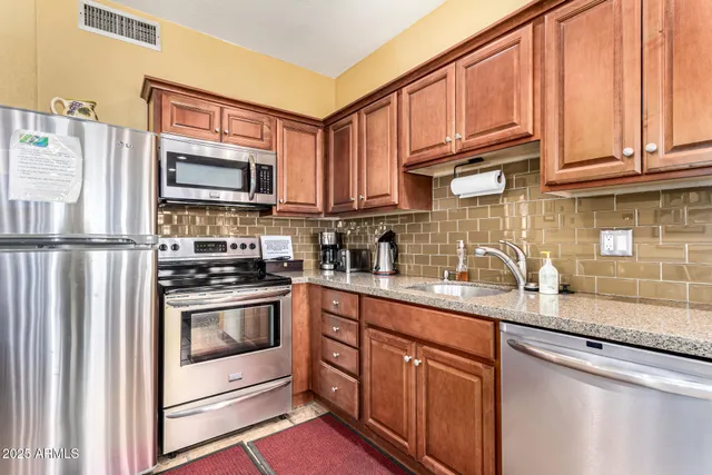 a kitchen with stainless steel appliances granite countertop a refrigerator stove microwave and sink