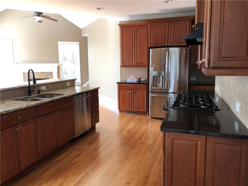 2575 Goodrick Lane Cumming, GA 30041 - Photo 10 of 30 a kitchen with granite countertop wooden floors a stove and a refrigerator