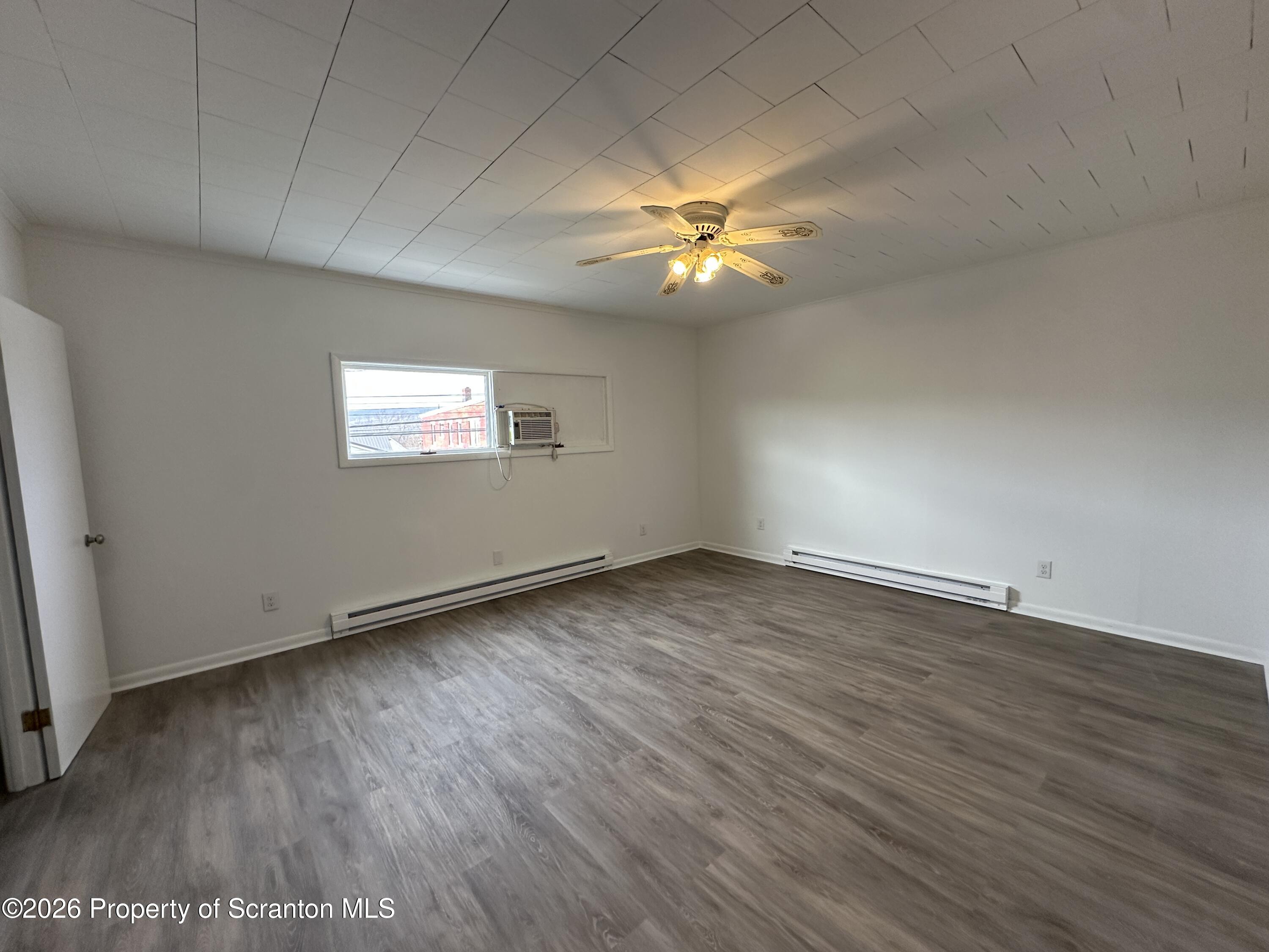 732 Main Street Avoca, PA 18641 - Photo 11 of 14 an empty room with wooden floor and windows